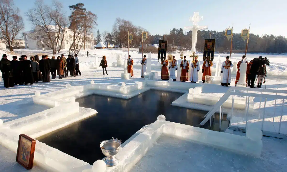 Ополонка у вигляді хреста. Довкола люди і священники.