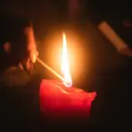 Жінка запалює свічку.