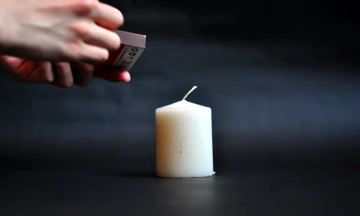 Жінка запалює свічку сірниками.