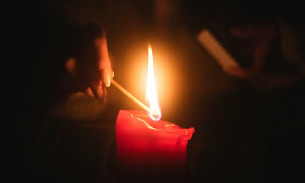 Жінка запалює свічку.