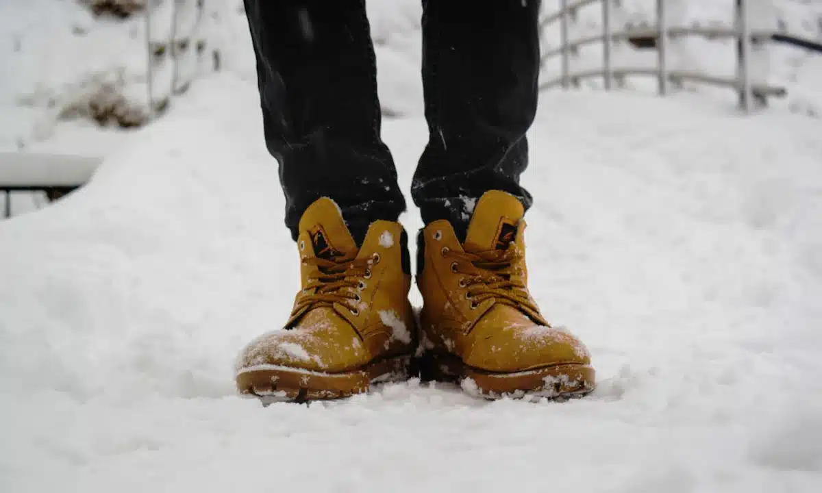 Чоловік стоїть у зимовому взутті на снігу.