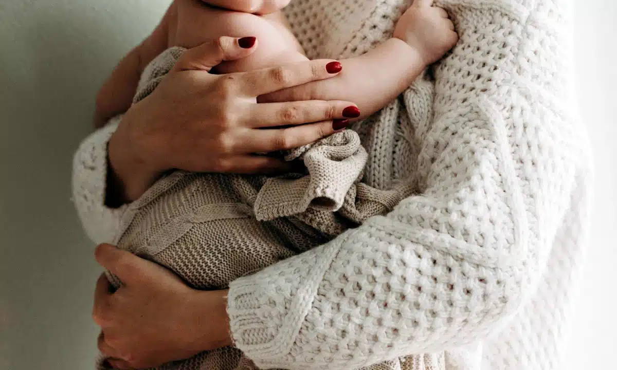 Мама тримає немовля на руках.