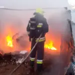 Рятувальник гасить полум'я в гаражі, що палає.