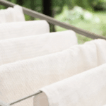 Біла постільна білизна після прання сушиться на сушарці на відкритому повітрі