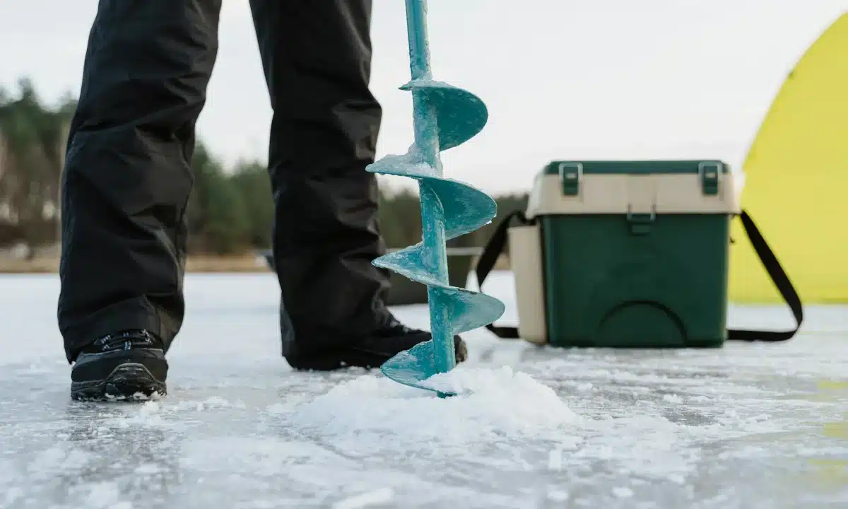 Рибалка бурить дірку в льоду.