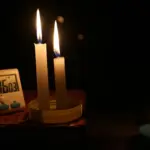 На столі горять три свічки, поряд годинник.