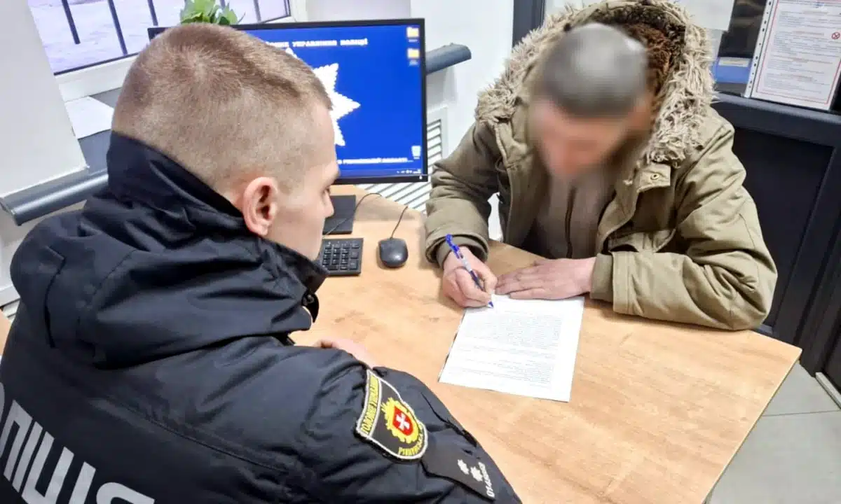 Зловмисник у відділку поліції підписує папери.