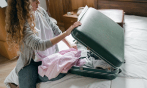 Жінка збирає валізу.